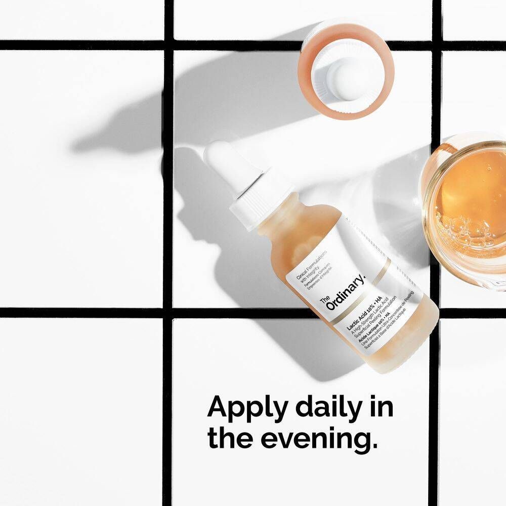 Flacon en verre avec pipette et texte. Texte : Apply daily in the evening. Sur fond blanc.