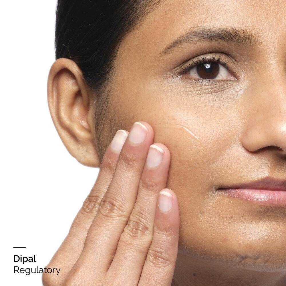 Nahaufnahme einer Person, die ein Produkt auf die Haut aufträgt. Nur Gesicht und Hand sichtbar.