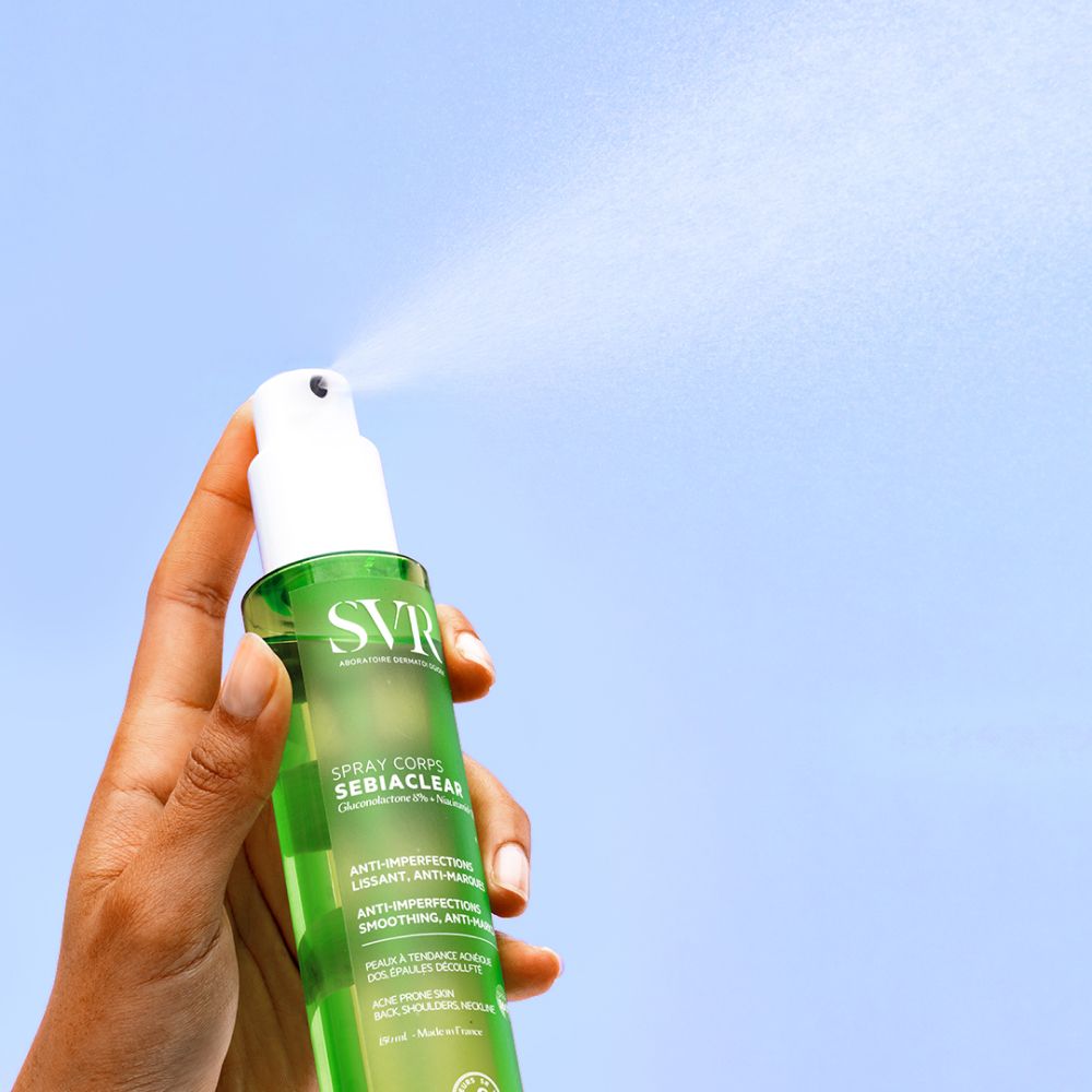 Main tenant flacon vert avec vaporisateur blanc. Vaporisation. SVR Sebiaclear Spray Corps.