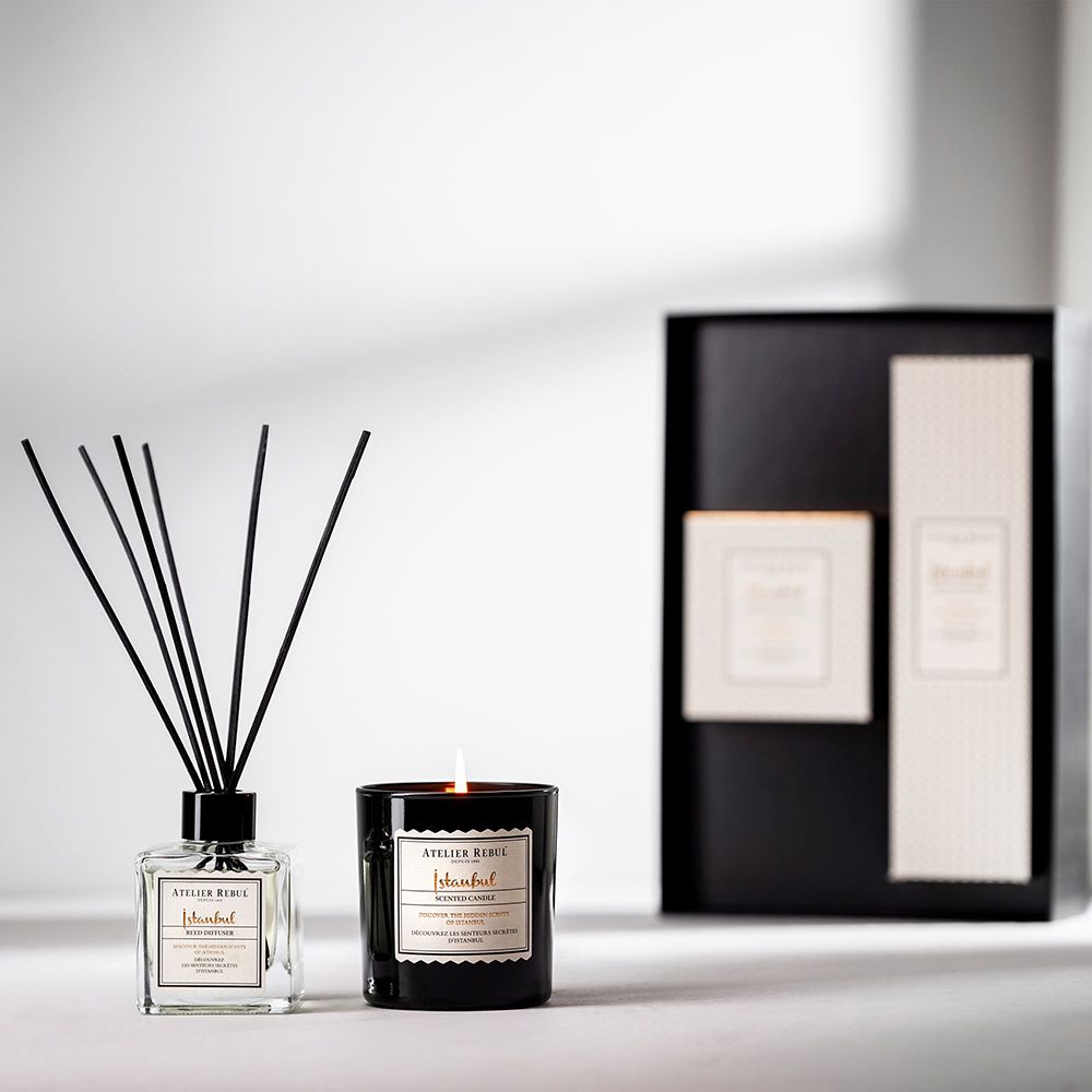 Bâtonnets parfumés, bougie et coffret cadeau. Bougie allumée. Marque : ATELIER REBUL. Nom du produit : Istanbul. Emballage noir.
