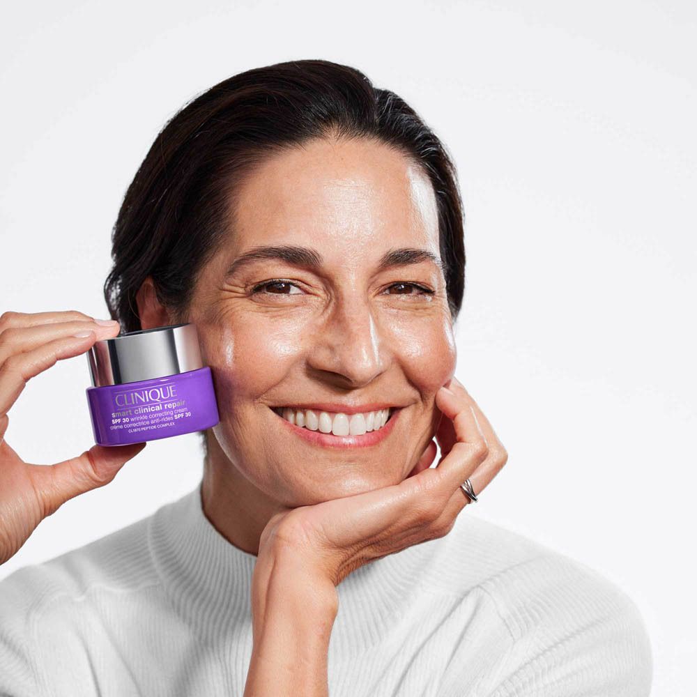 Frau hält eine lila Clinique Feuchtigkeitscreme mit SPF 20.