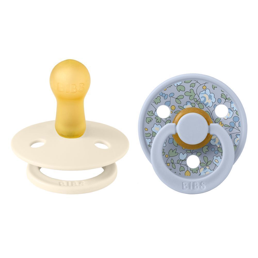 Deux sucettes. Une crème et une bleue à motifs floraux. Logo BIBS sur l'anneau.
