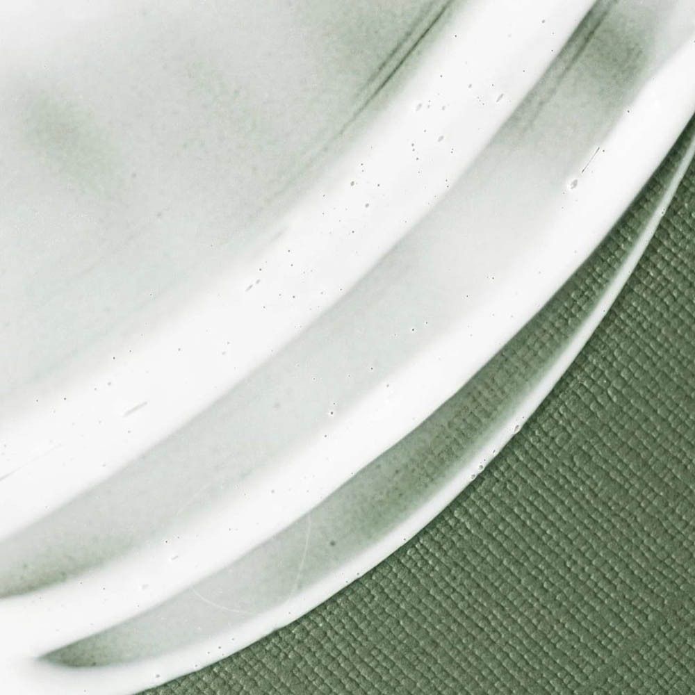 Gros plan de crème blanche sur fond vert. Texture ondulée s'étendant sur la surface.