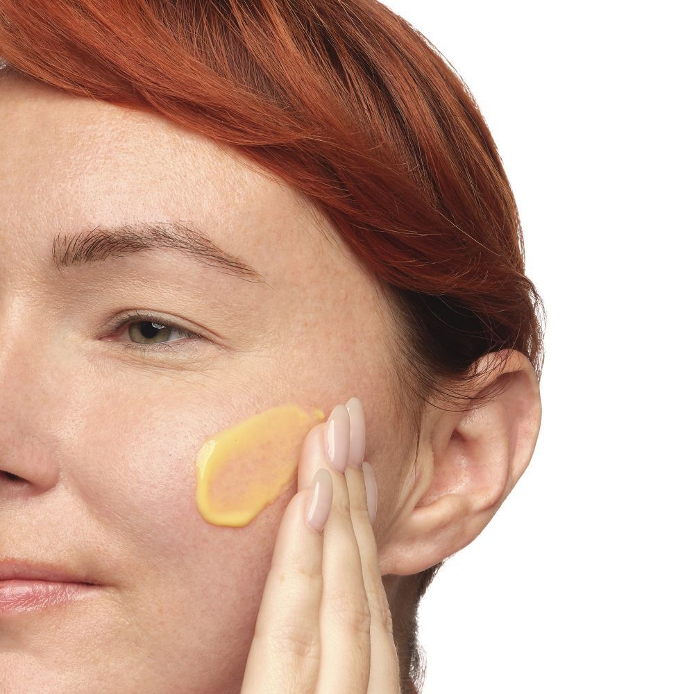 Gesicht mit gelber Flüssigkeit auf der Haut. Person berührt die Haut.