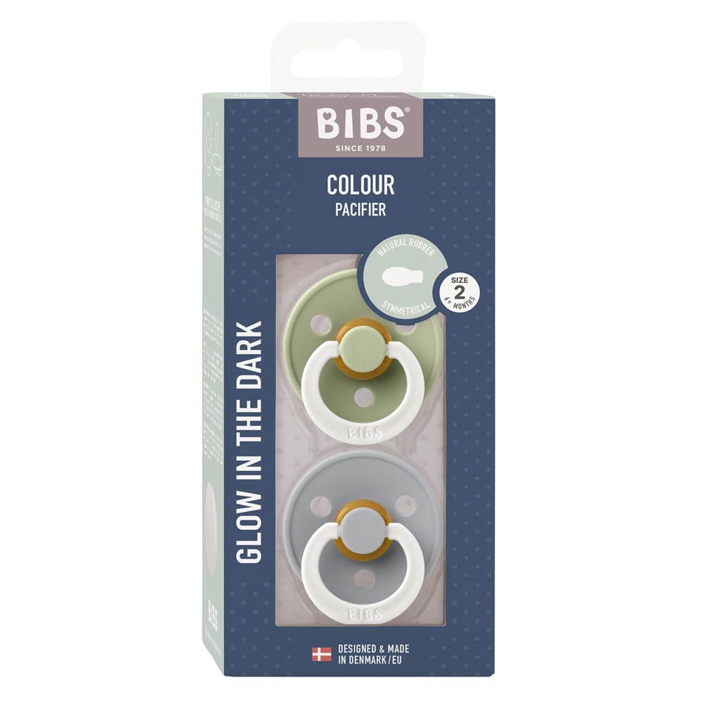 Verpackung mit zwei Schnullern. Sichtbar: zwei Schnuller in Grün und Blau, mit weißem Ring und braunem Element. Marke BIBS.