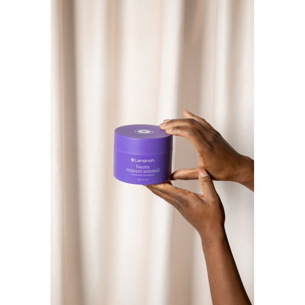 Hände halten lila Tiegel. Text: Lansinoh, Baume relaxant sommeil, 200 ml.