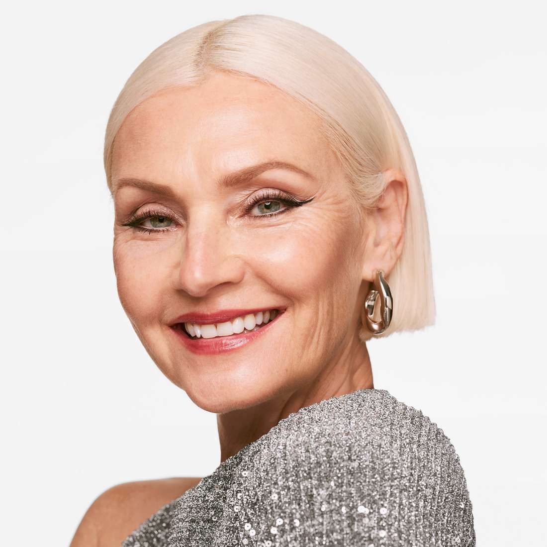 Porträt einer Frau mit Make-up. Sie lächelt. Sie trägt Ohrringe.