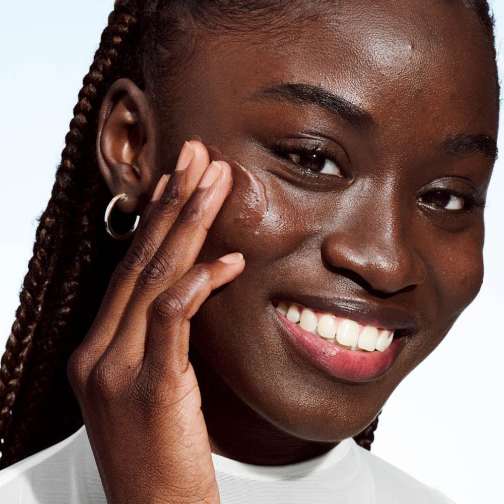 Femme appliquant du maquillage. Nom et détails du produit non visibles. Égalisation du teint.