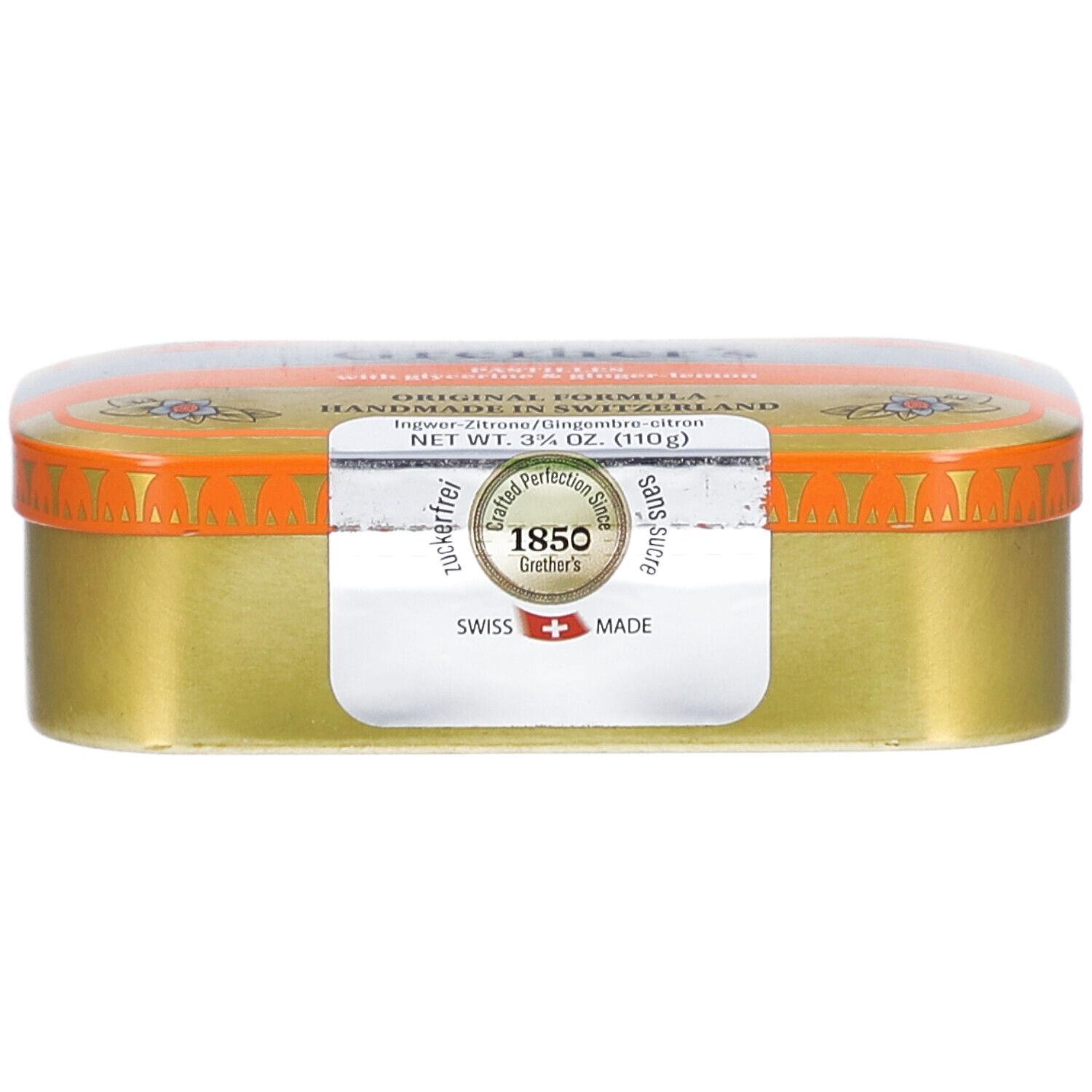 Goldfarbene Pastillendose mit orangefarbenem Deckel. Aufkleber mit Text. "Swiss Made".