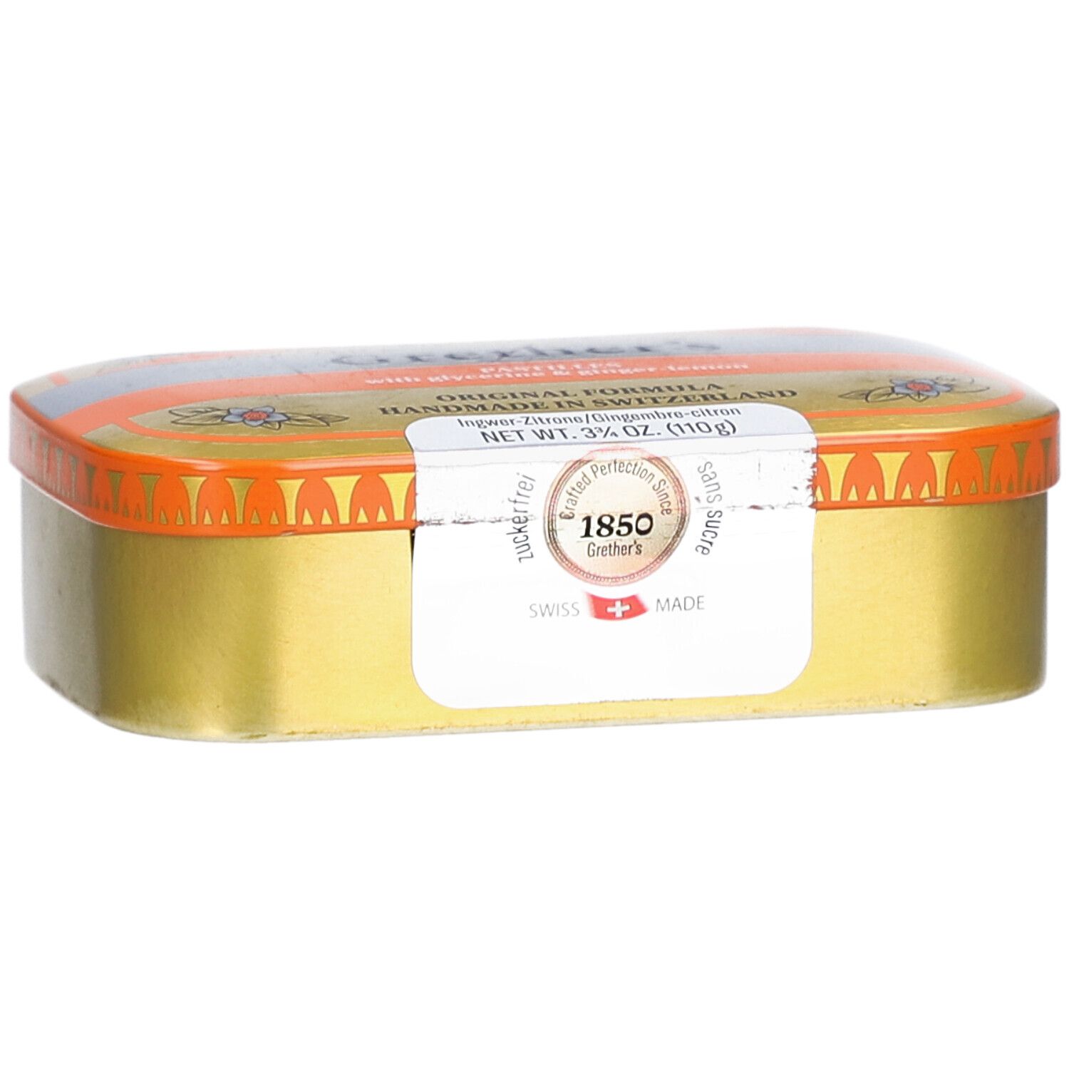 Goldfarbene Pastillendose mit orangefarbenem Deckel. Aufkleber mit Text. "Swiss Made".