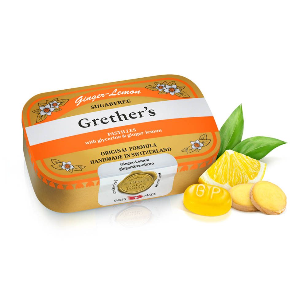 Boîte dorée avec couvercle orange. Citron, gingembre et pastilles à côté. Inscription : Ginger-Lemon, Sugarfree.