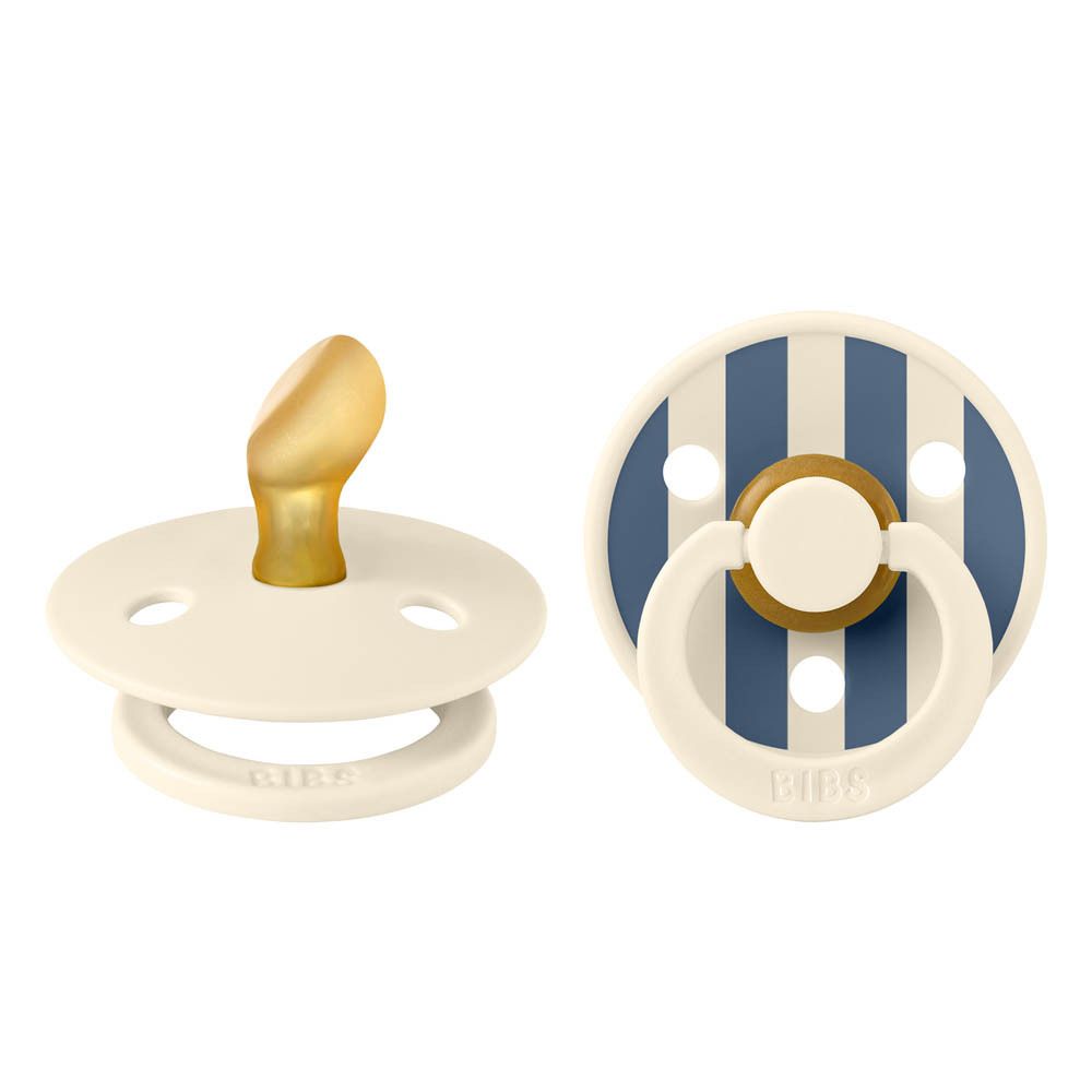 Deux sucettes. Tétine anatomique, crème. Bouclier à rayures bleues et blanches avec logo BIBS.