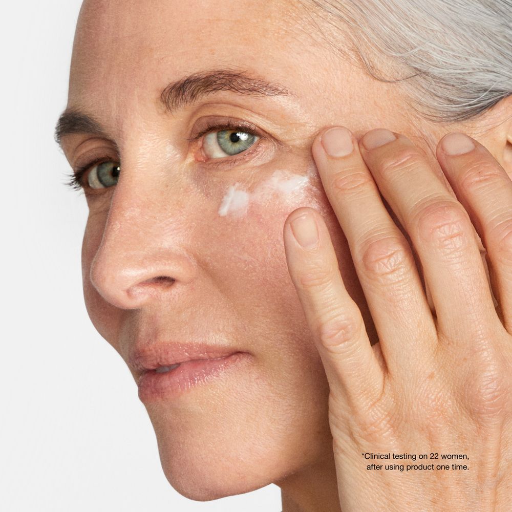 Femme appliquant de la crème sur le contour des yeux. Crème blanche sur la peau.