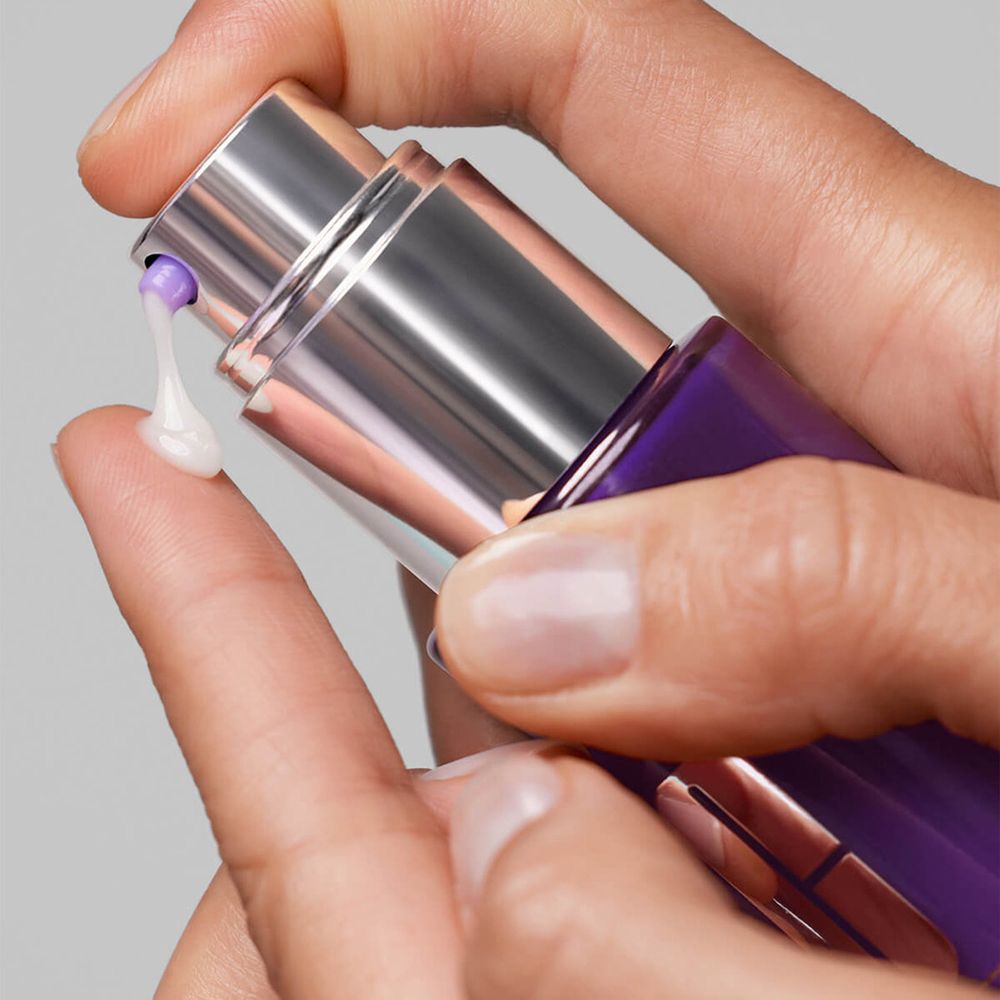 Hände drücken Serum auf den Finger. Lila Flasche mit silbernem Sprühkopf.
