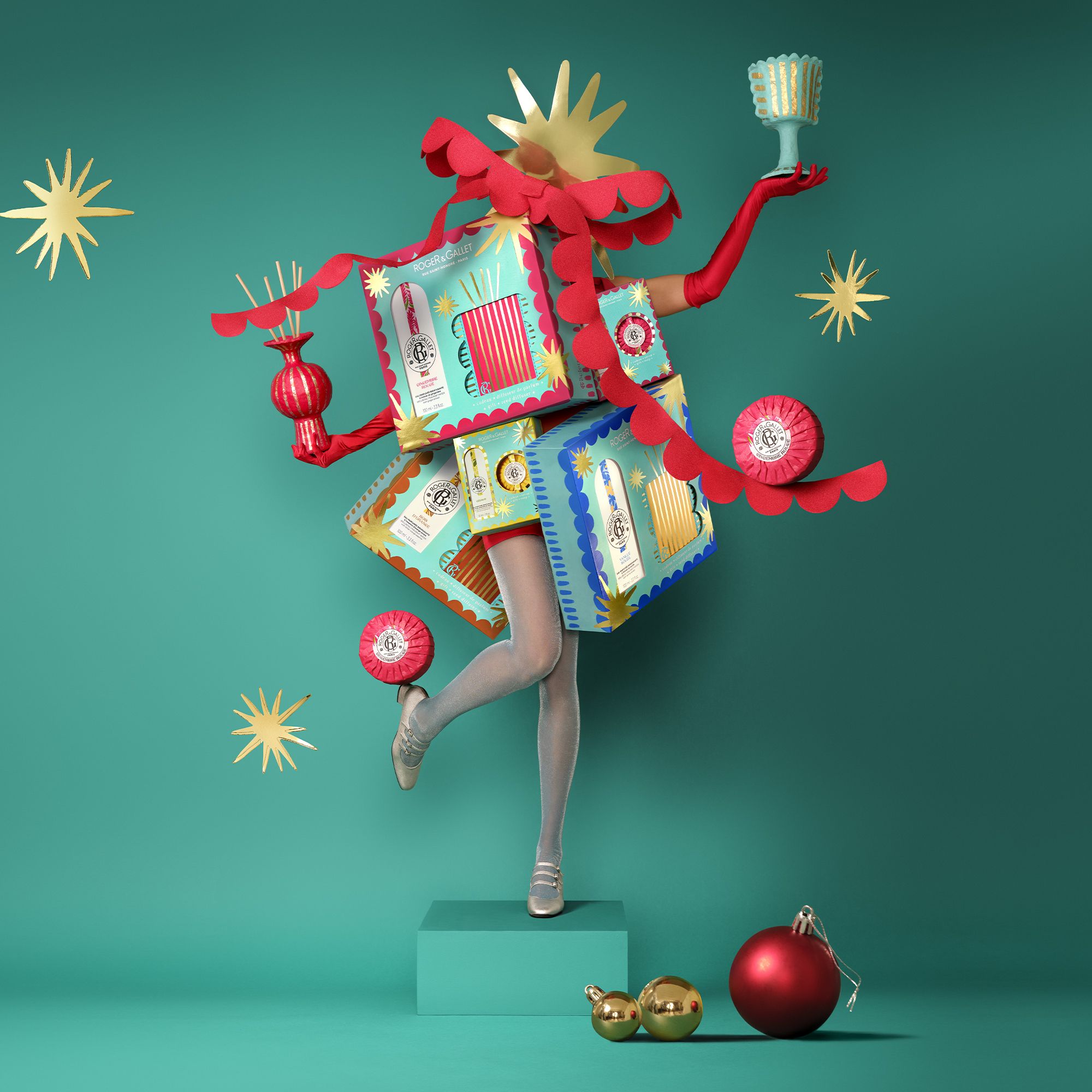 Présentation du produit avec des coffrets cadeaux. Femme avec coffrets cadeaux en costume. Emballages turquoise et rose. Texte: Roger & Gallet.