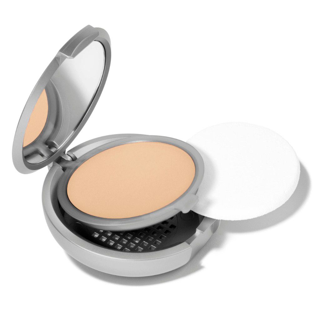 Fond de teint compact ouvert. Miroir, poudre et applicateur. Boîtier argenté.