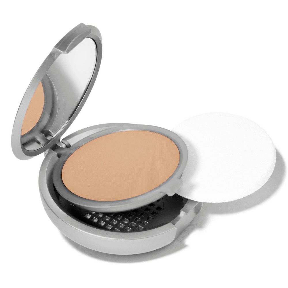 Compact poudré argenté ouvert avec miroir et éponge. Poudre beige.