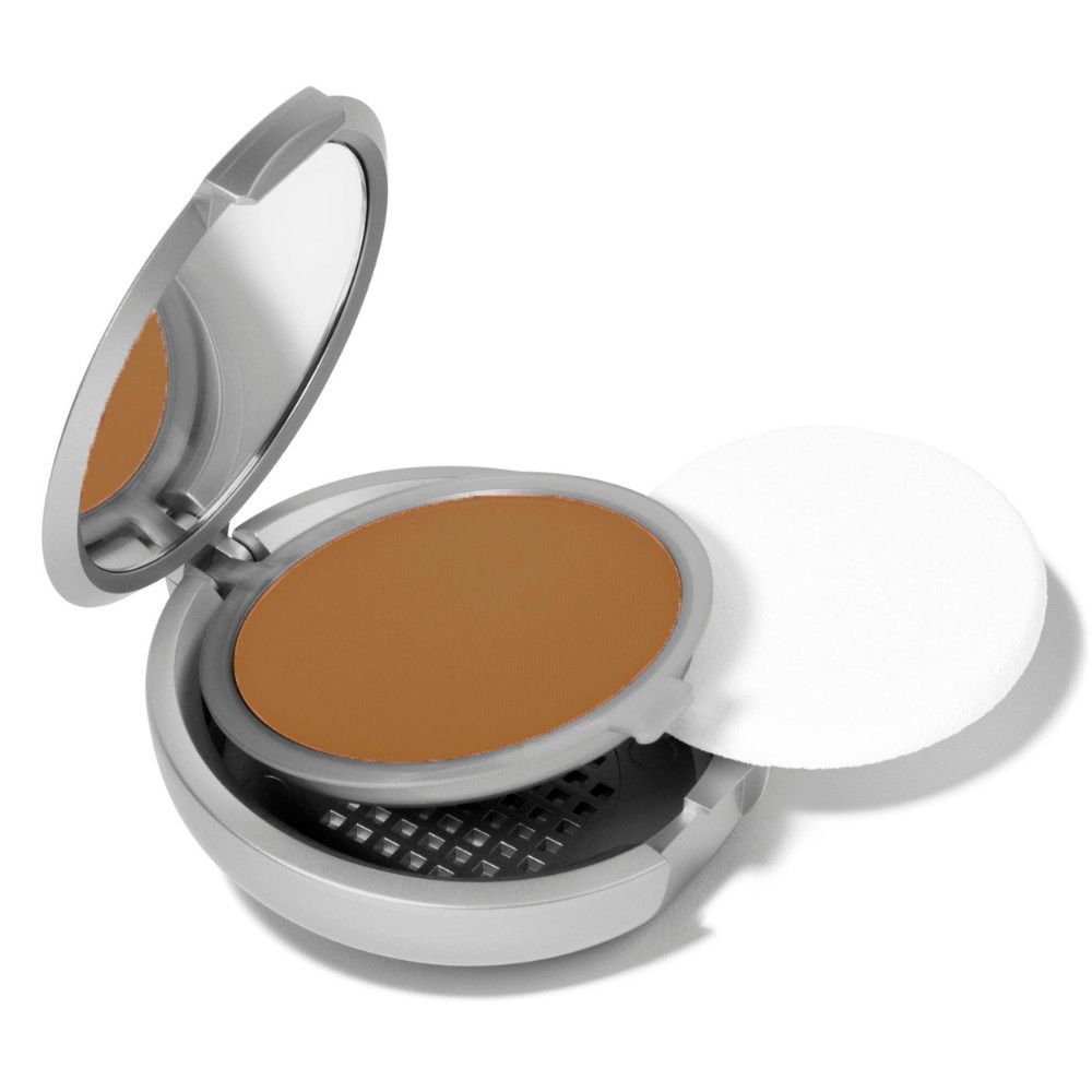 Boîtier compact rond argenté, ouvert. Poudre brune. Couvercle ouvert.