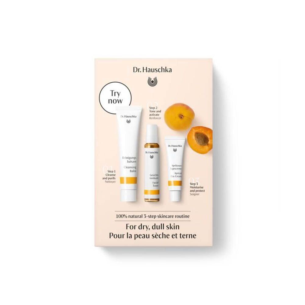 Coffret cadeau avec trois produits de soin et des abricots. Inscription : Dr. Hauschka, routine en 3 étapes pour peau sèche.