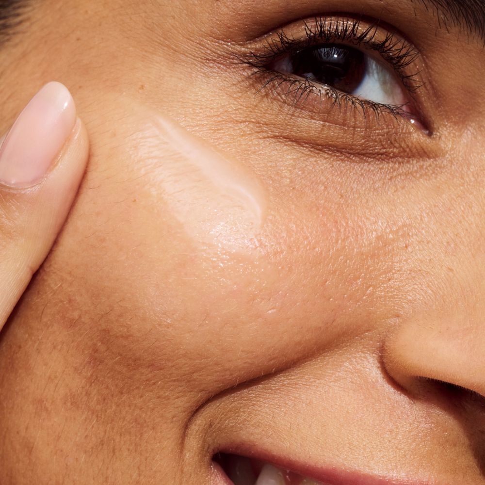 Personne appliquant du sérum sur le visage. Nom de la marque ou du produit non visible.