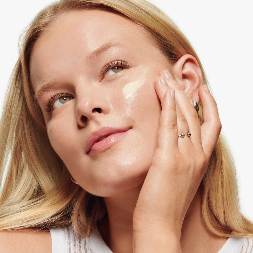 Frau trägt Creme auf das Gesicht auf. Produkt: Clinique Dramatically Different Moisturizing Lotion.