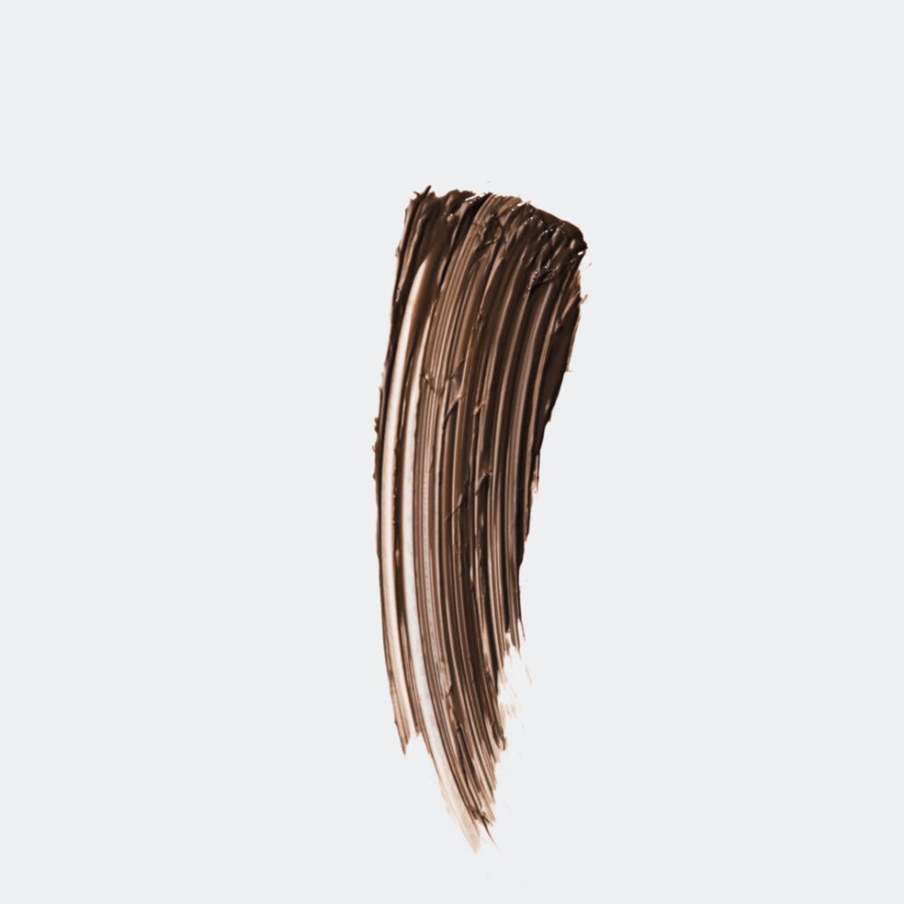 Gel à sourcils brun sur fond blanc. Texture avec coups de pinceau.