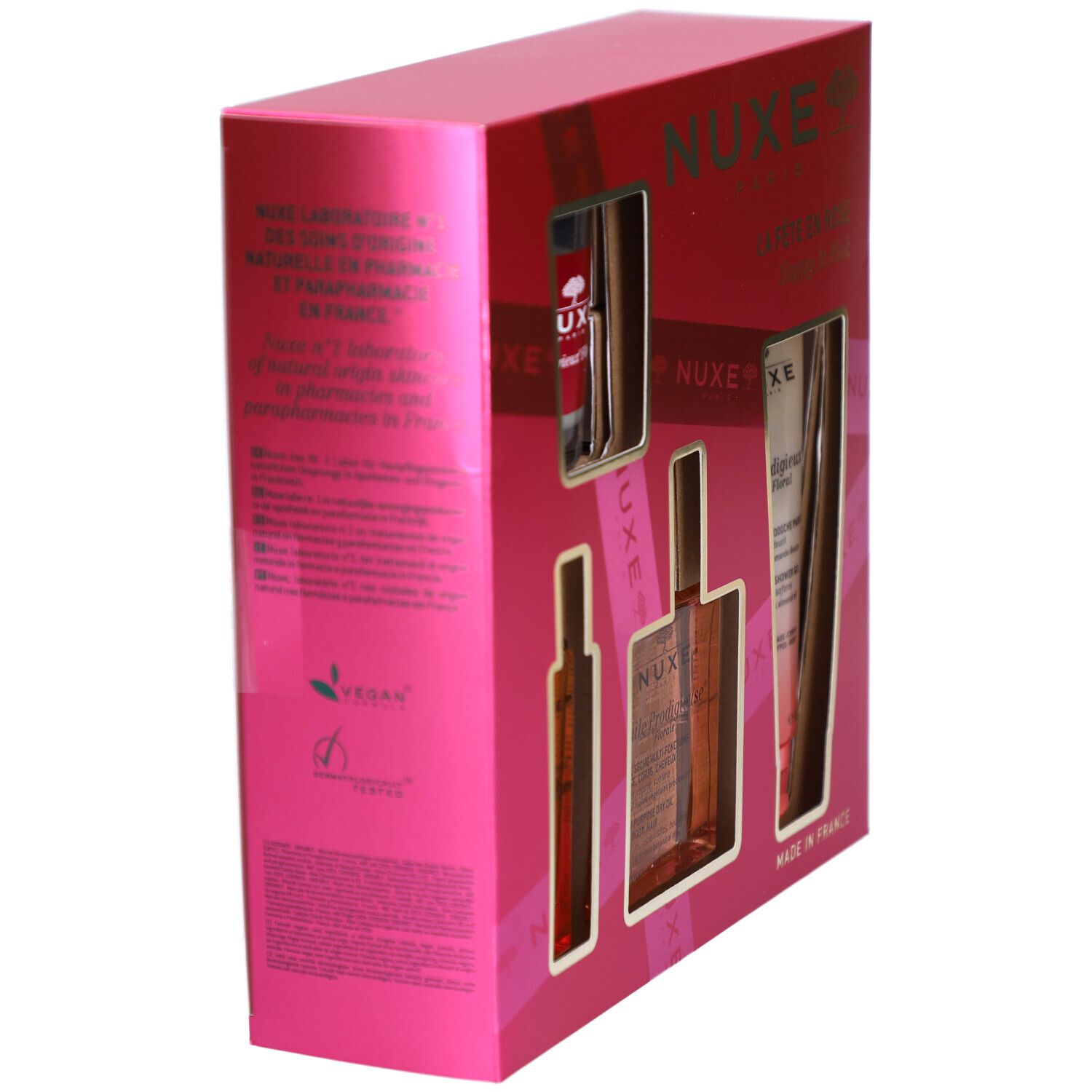 Coffret rose incliné, vue latérale. Produits visibles à travers les ouvertures. Logo et texte Nuxe.