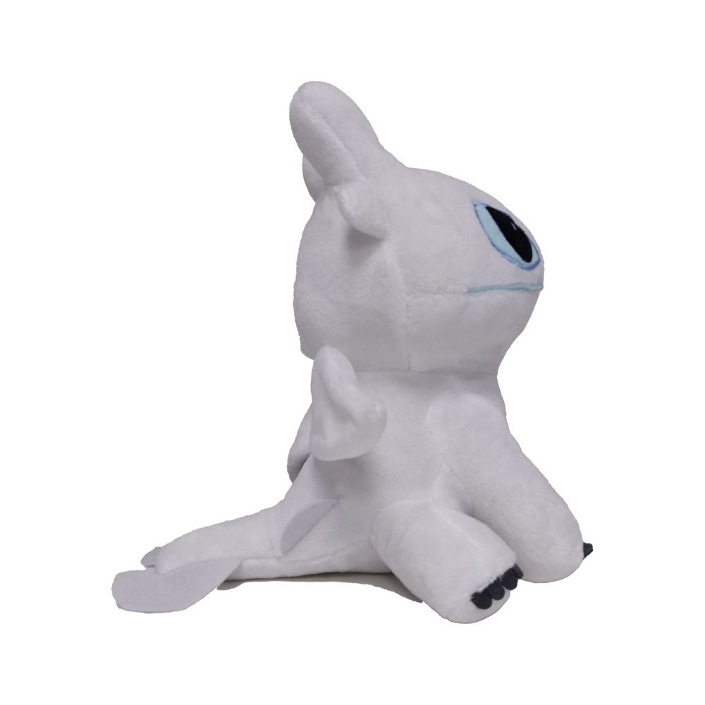 Peluche blanc, vue latérale. Forme de dragon, yeux bleus, ailes. Position couchée.