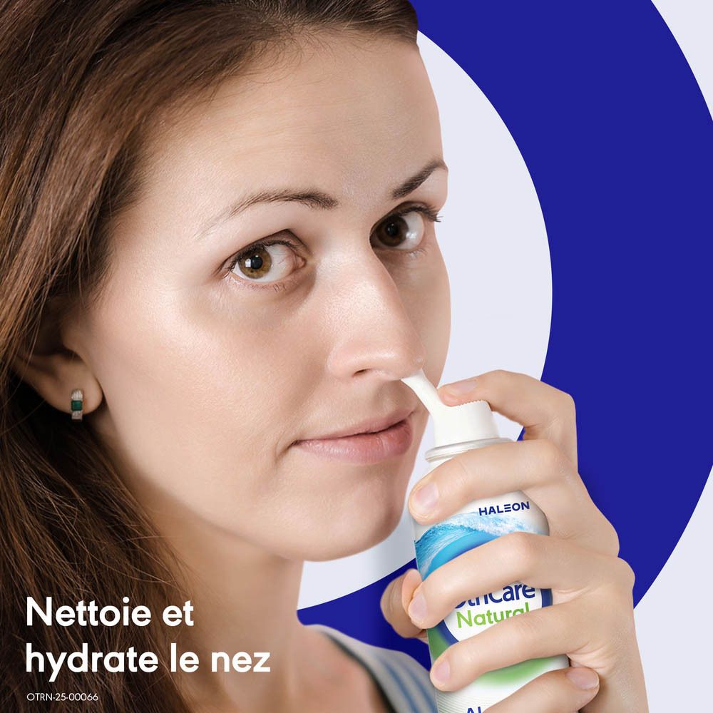 Femme utilisant un spray nasal. OtriCare Natural. Mur bleu et blanc en arrière-plan. Texte: Nettoie et hydrate le nez.