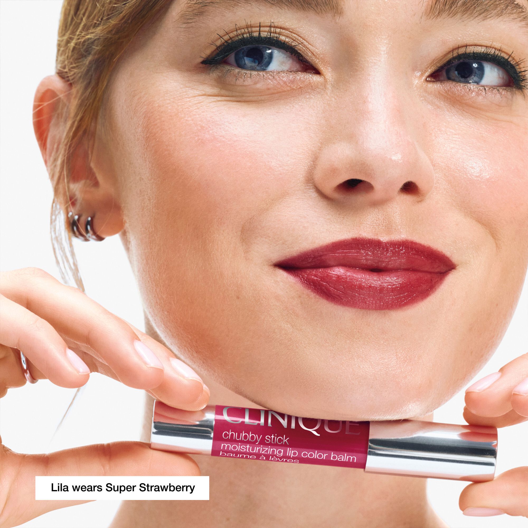 Frau mit Lippenstift. Lippenstift in Super Strawberry. Produktname und Marke sichtbar.