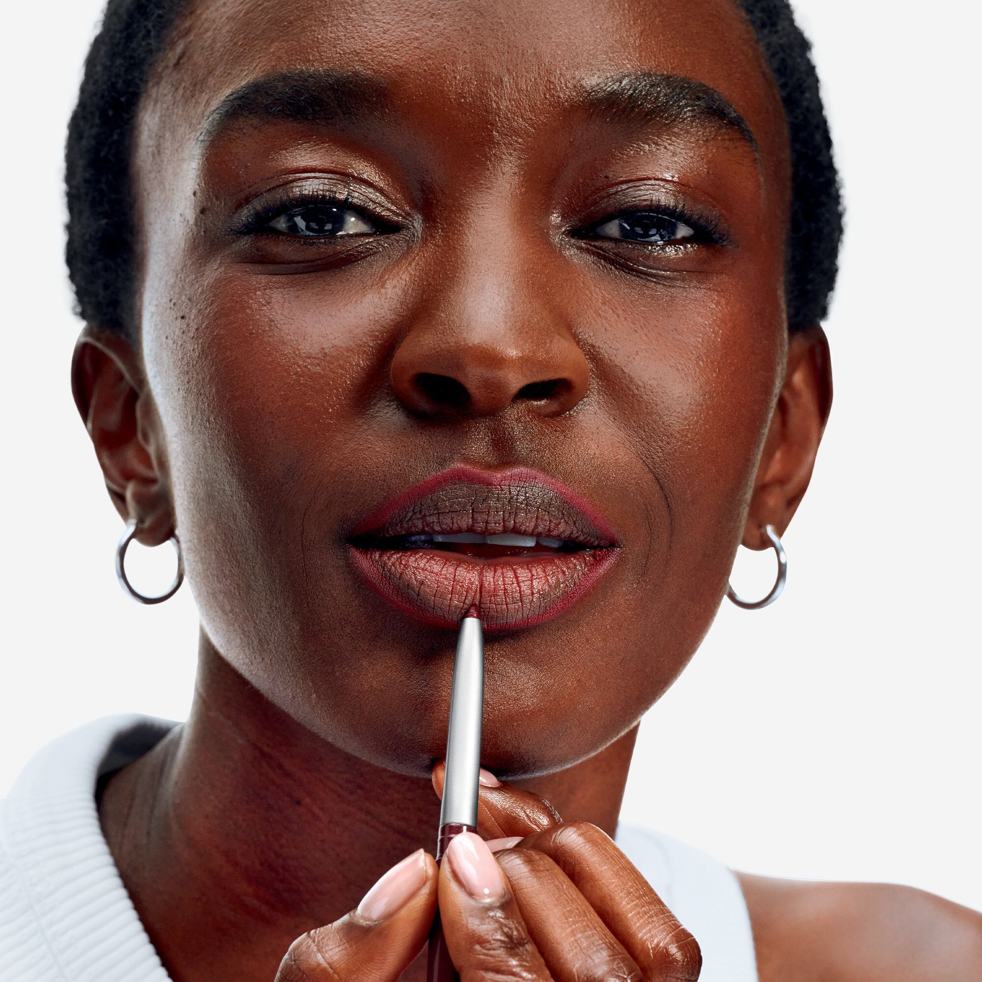 Nahaufnahme einer Frau, die ihre Lippen mit einem Lippenkonturenstift umrandet. Silberner Stift.