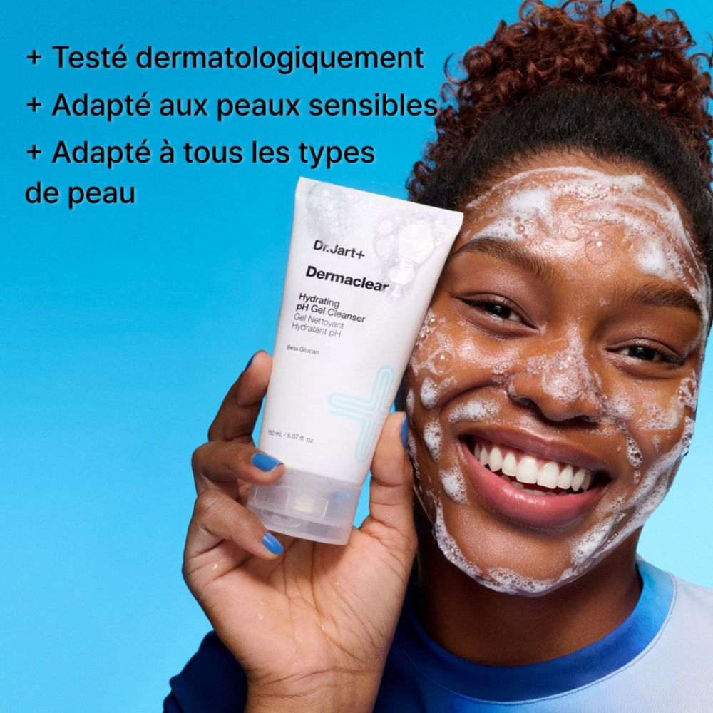 Eine lächelnde Frau mit schäumendem Gel-Reiniger auf dem Gesicht hält eine Tube Dr.Jart+ Dermaclear Hydrating pH Gel Cleanser.