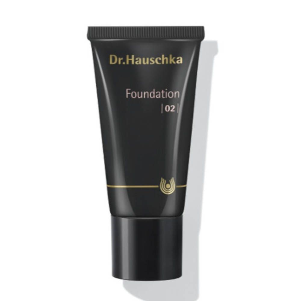 Tube noire avec texte doré. "Dr. Hauschka" en haut, "Foundation 02" en dessous. Logo doré en bas.