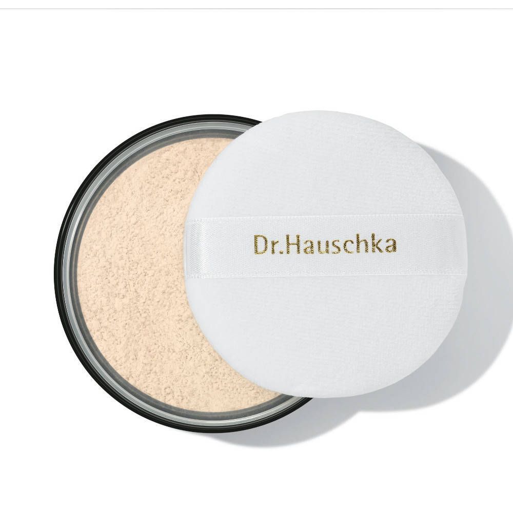 Runder Behälter mit losem Puder und einem weißen Puderquaste. Auf dem Puderquaste steht "Dr. Hauschka".