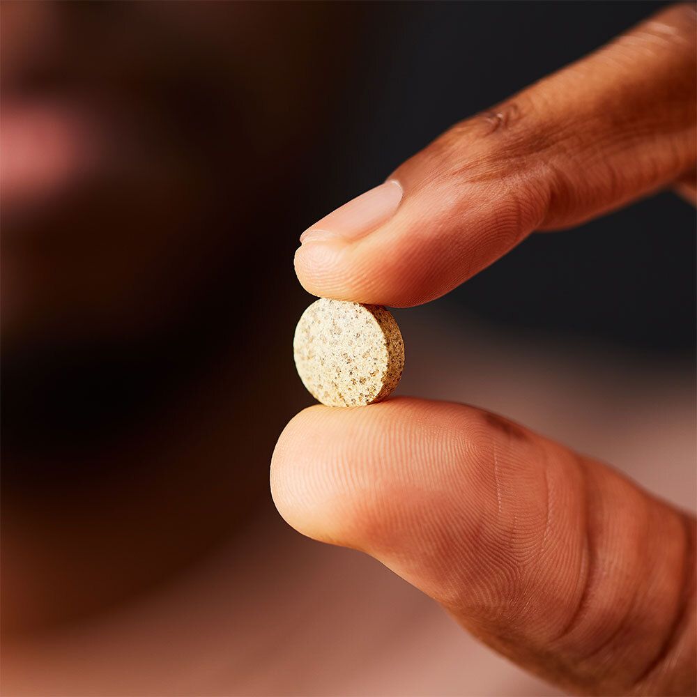 Hand hält Tablette. Tablette zwischen Daumen und Zeigefinger.