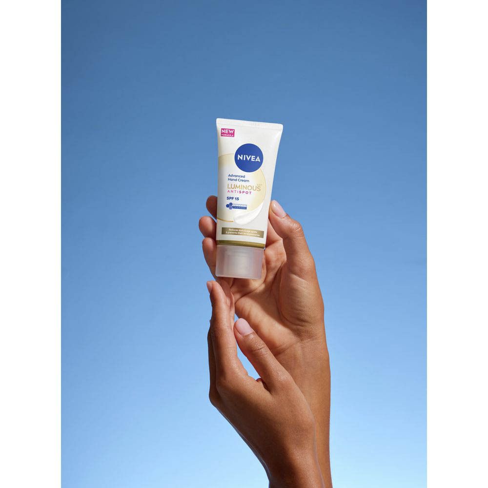 Mains d'une personne avec une touche de crème mains NIVEA® sur le dos de la main, près d'une tasse à café sur un plateau.