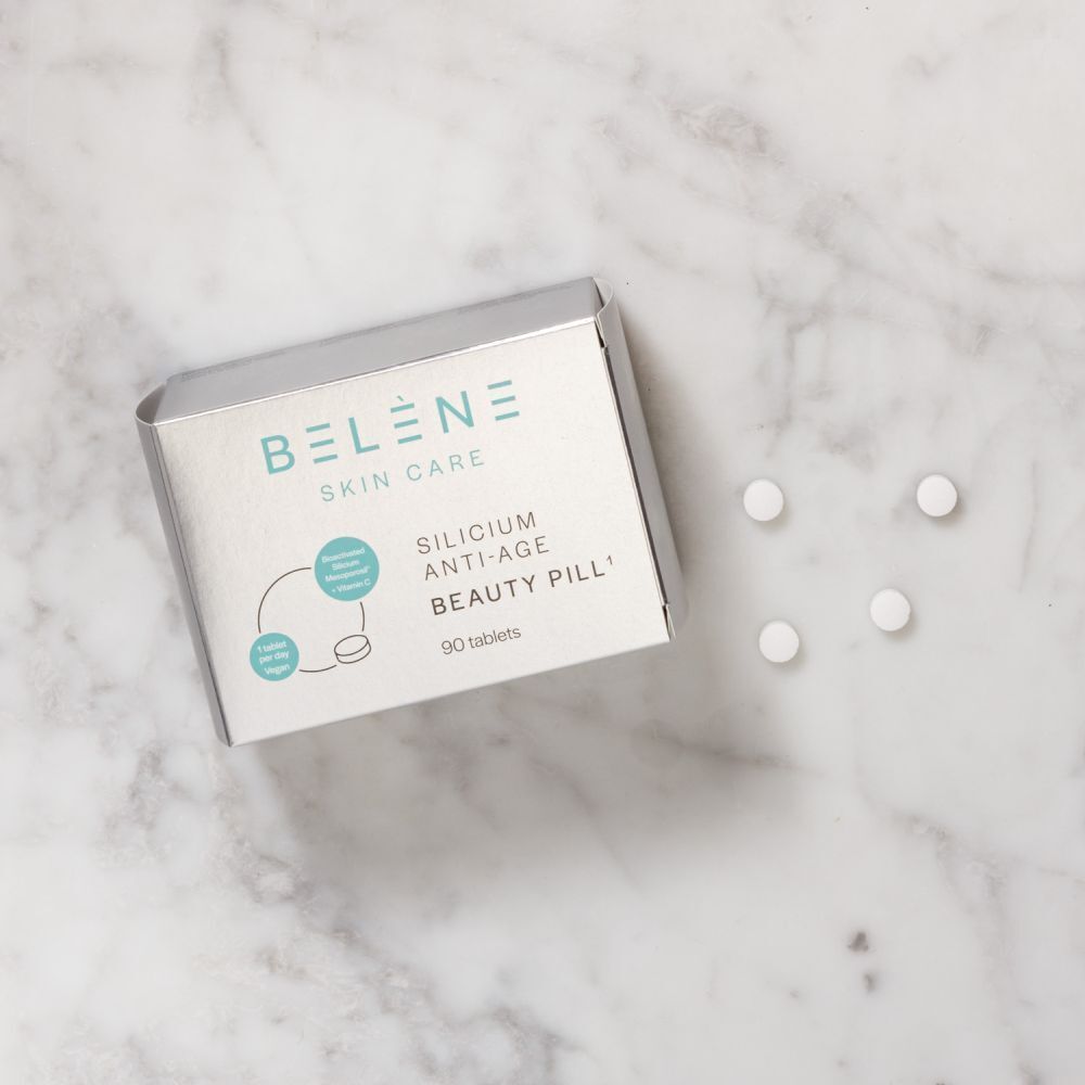BELÈNE Skin Care Silicium Anti-Age Beauty Pillen (90 Tabletten) mit vier einzelnen Tabletten auf Marmoruntergrund.