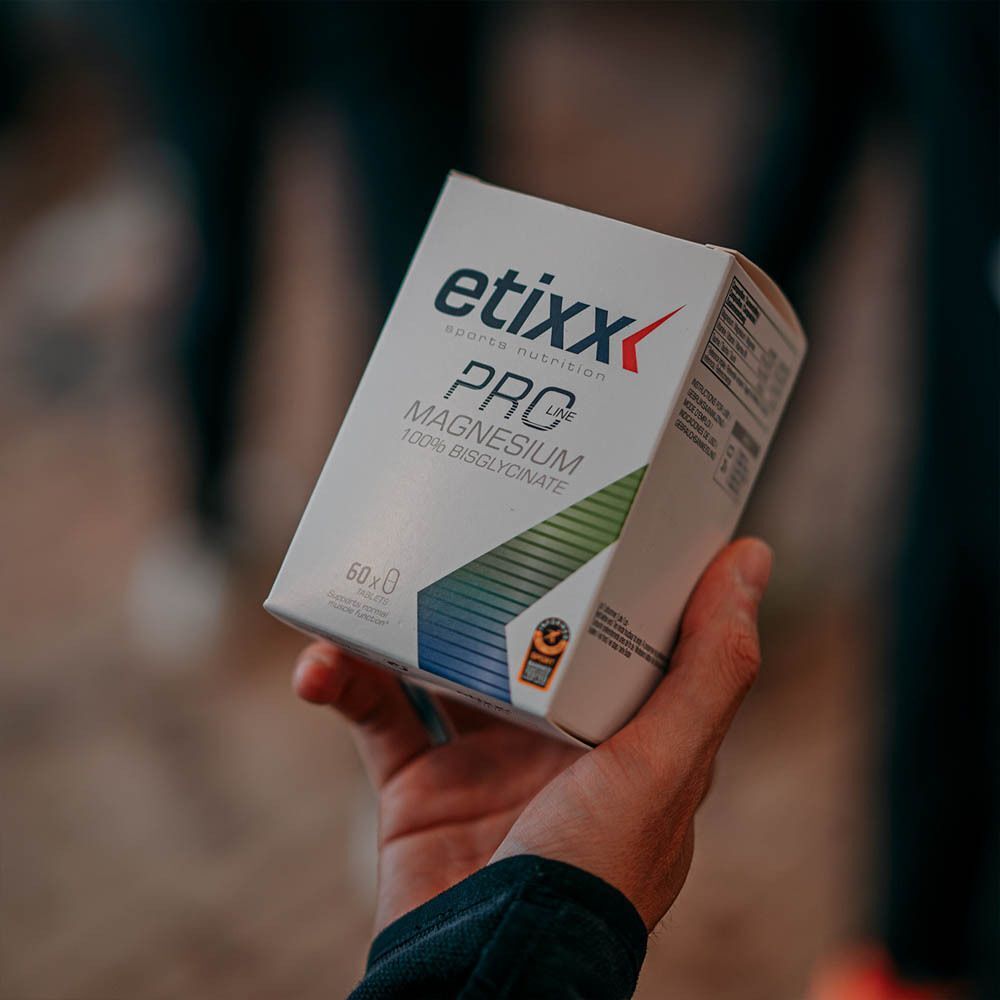 Eine Hand hält eine weiße Schachtel mit der Aufschrift etixx PRO Magnesium 100% Bisglycinat. Aufdruck: 60x.
