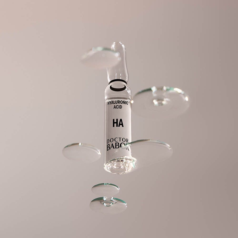 Klare Ampulle mit Flüssigkeit. Aufschrift: HA, Hyaluronsäure, Doctor BABOR. Steht auf Sockel.