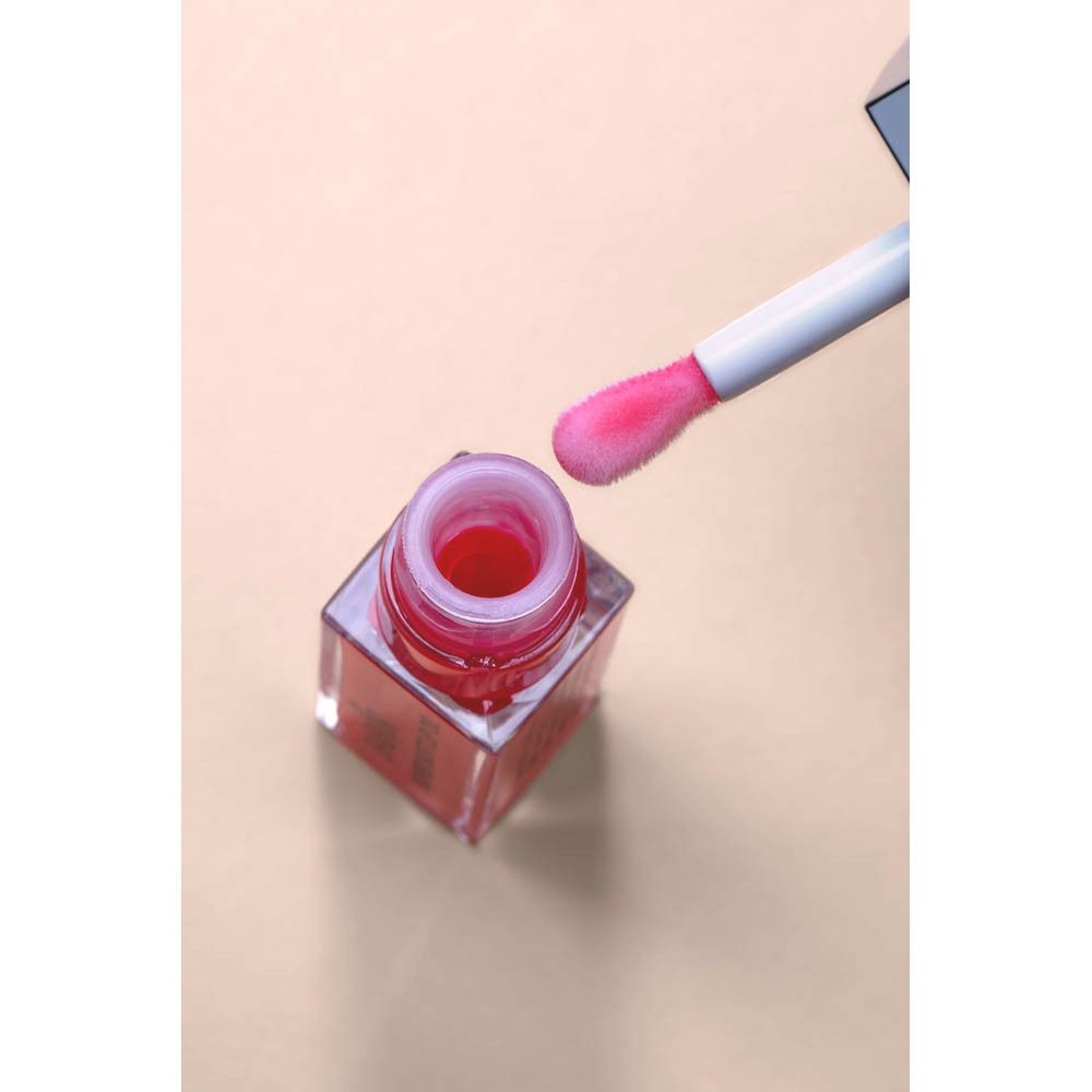 Flacon d'huile à lèvres ouvert avec applicateur. Contenu rose. Brosse applicateur rose.