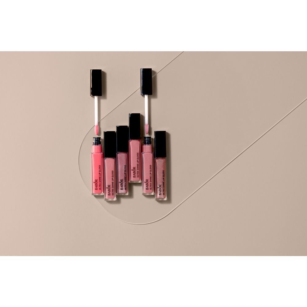 Mehrere Babor Ultra Shine Lip Gloss-Tuben. Rosa Inhalt. Schwarze Deckel. Auf hellem Hintergrund angeordnet.