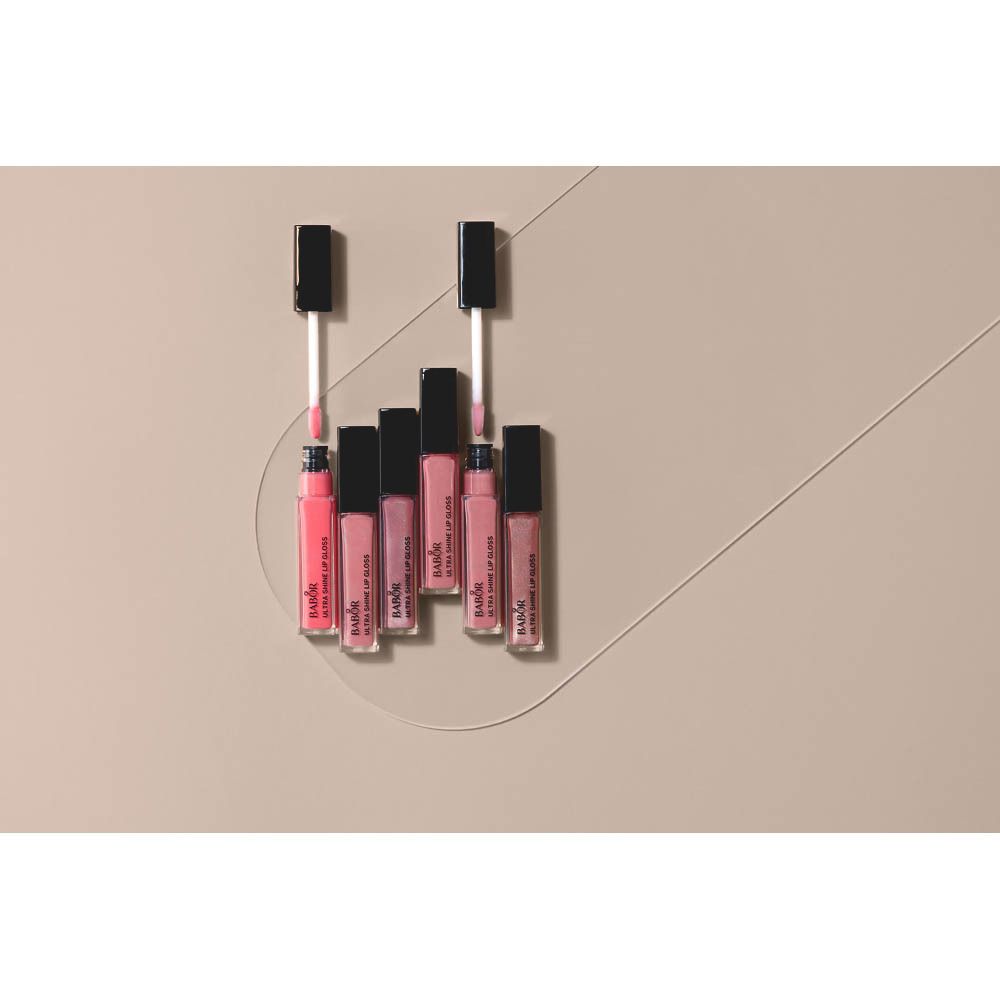 Mehrere Lipgloss-Fläschchen auf beigem Hintergrund. Marke und Produktname sichtbar.