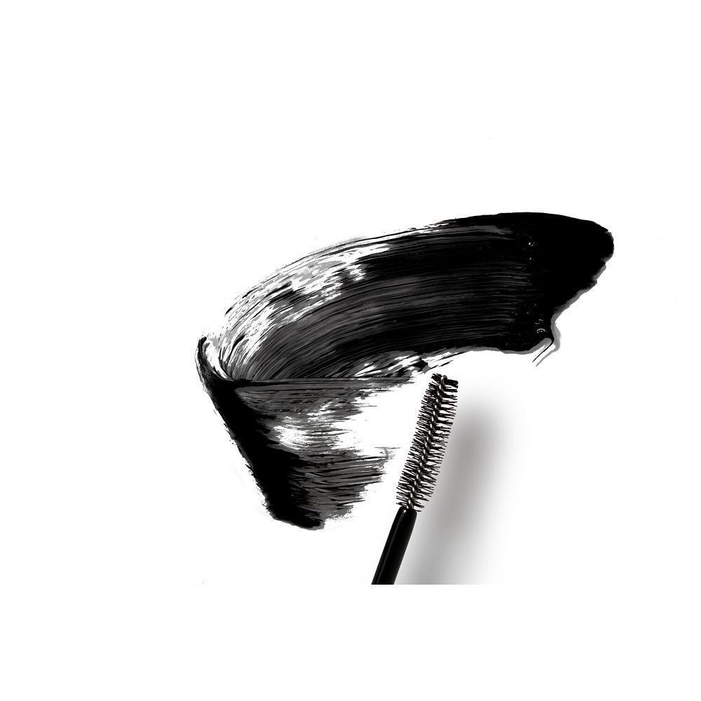 Application de mascara noir sur fond blanc. Brosse avec restes de mascara.