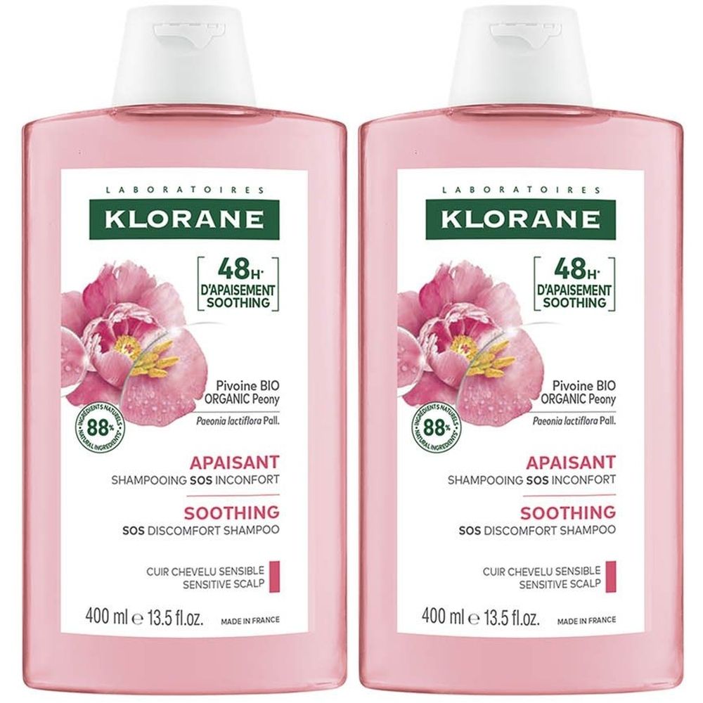 Deux flacons de shampooing Klorane. Liquide rose, bouchon blanc. Étiquette avec pivoine, texte : 88% ingrédients, 48H apaisant, cuir chevelu sensible.
