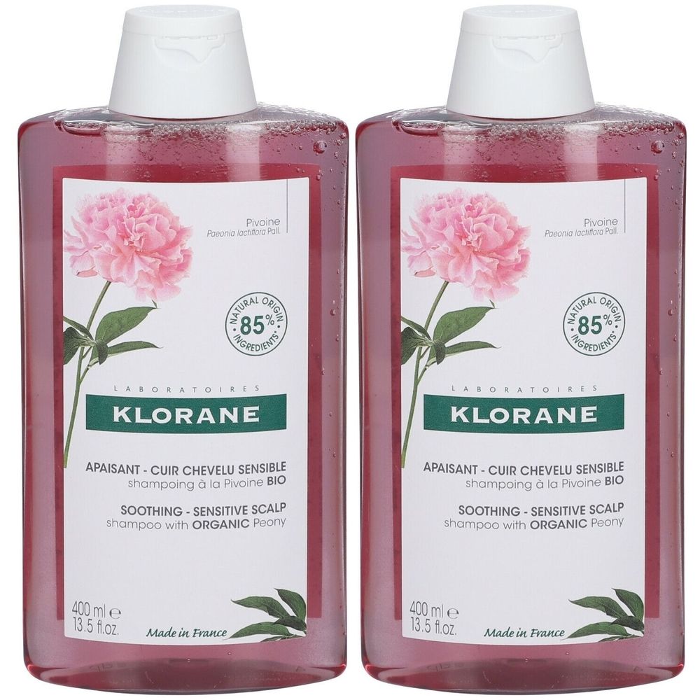 Deux flacons de shampooing Klorane. Liquide rose, bouchon blanc. Étiquette avec pivoine, texte : 85% ingrédients, apaisant, cuir chevelu sensible.