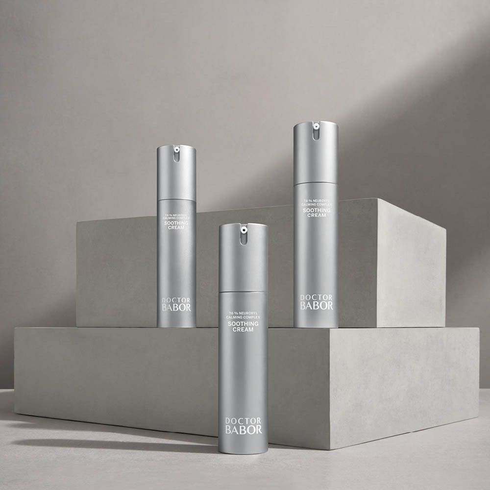 Trois flacons de crème argentés avec pompe. Inscription : Soothing Cream, Doctor Babor. Sur des socles.