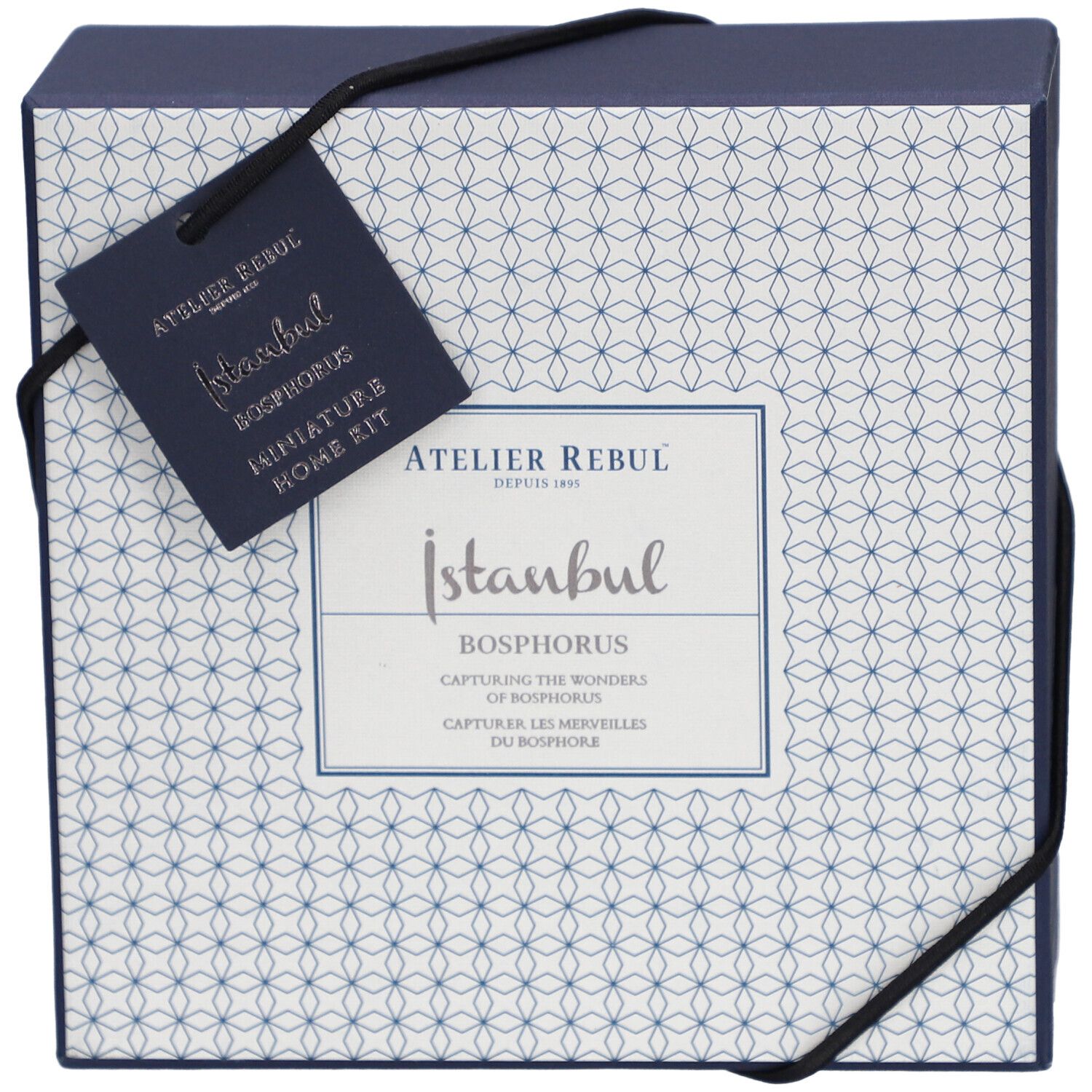 Dunkelblaue Schachtel mit weißem Muster und schwarzem Band. Anhänger mit Logo und Produktnamen.