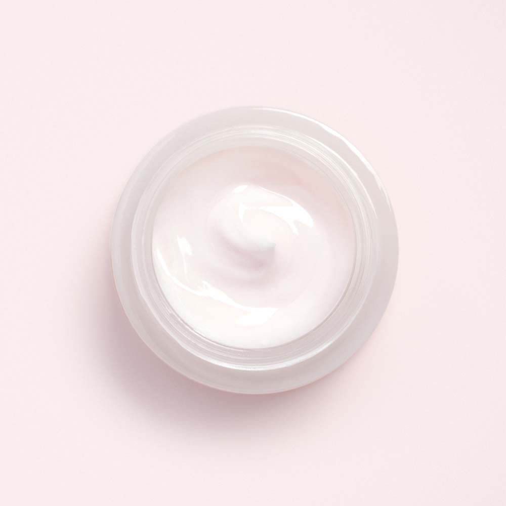 Pot de crème, vue de dessus. Texture de crème. Teinte rose-beige.
