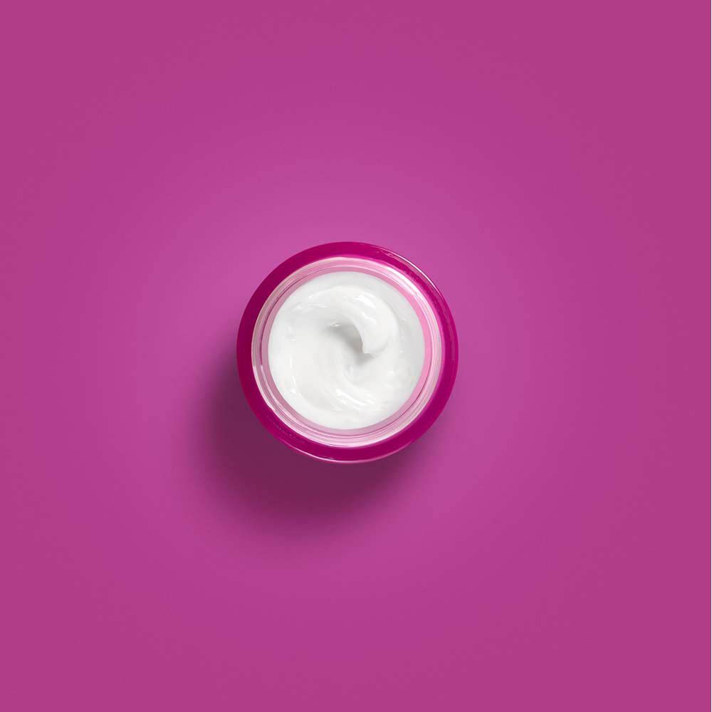 Vue de dessus d'un pot de crème rose. Crème blanche dans le pot.