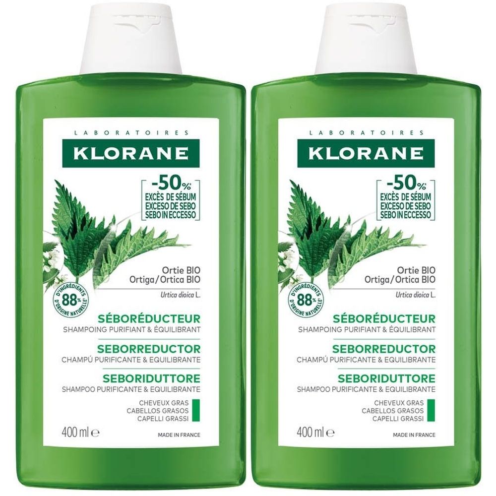 Deux flacons de shampooing KLORANE. Étiquette verte et blanche avec illustration d'ortie. Texte: Seboréducteur, -50% sébum.